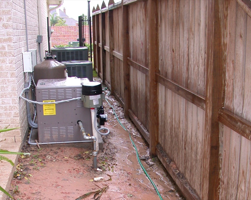 Equipos de bomba y climatización de una piscina instalados junto a una valla exterior