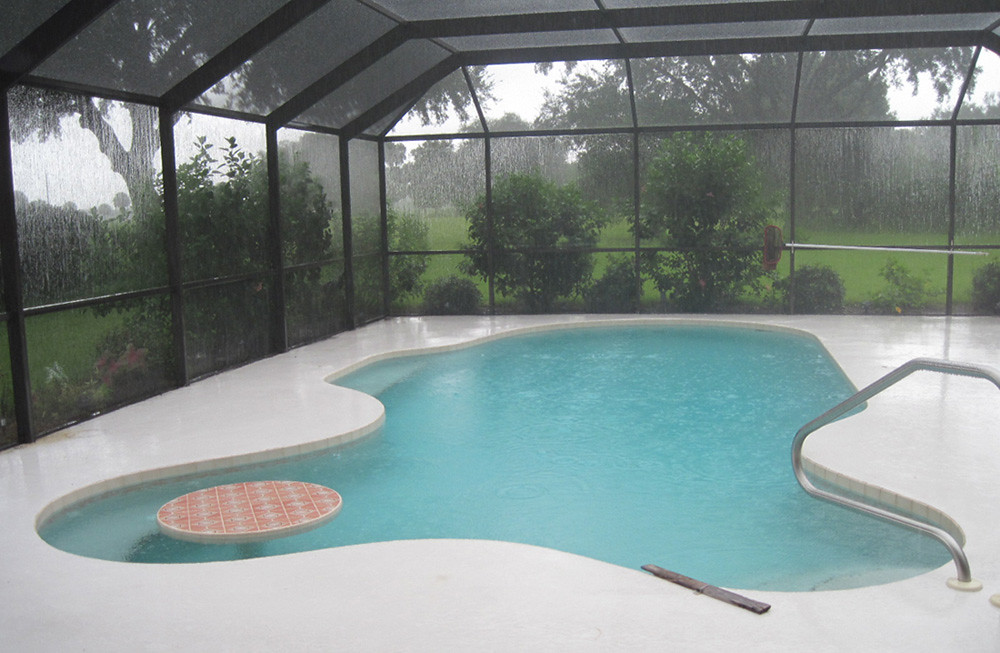 Piscina cubierta con estructura de tela mosquitera bajo una fuerte lluvia de verano
